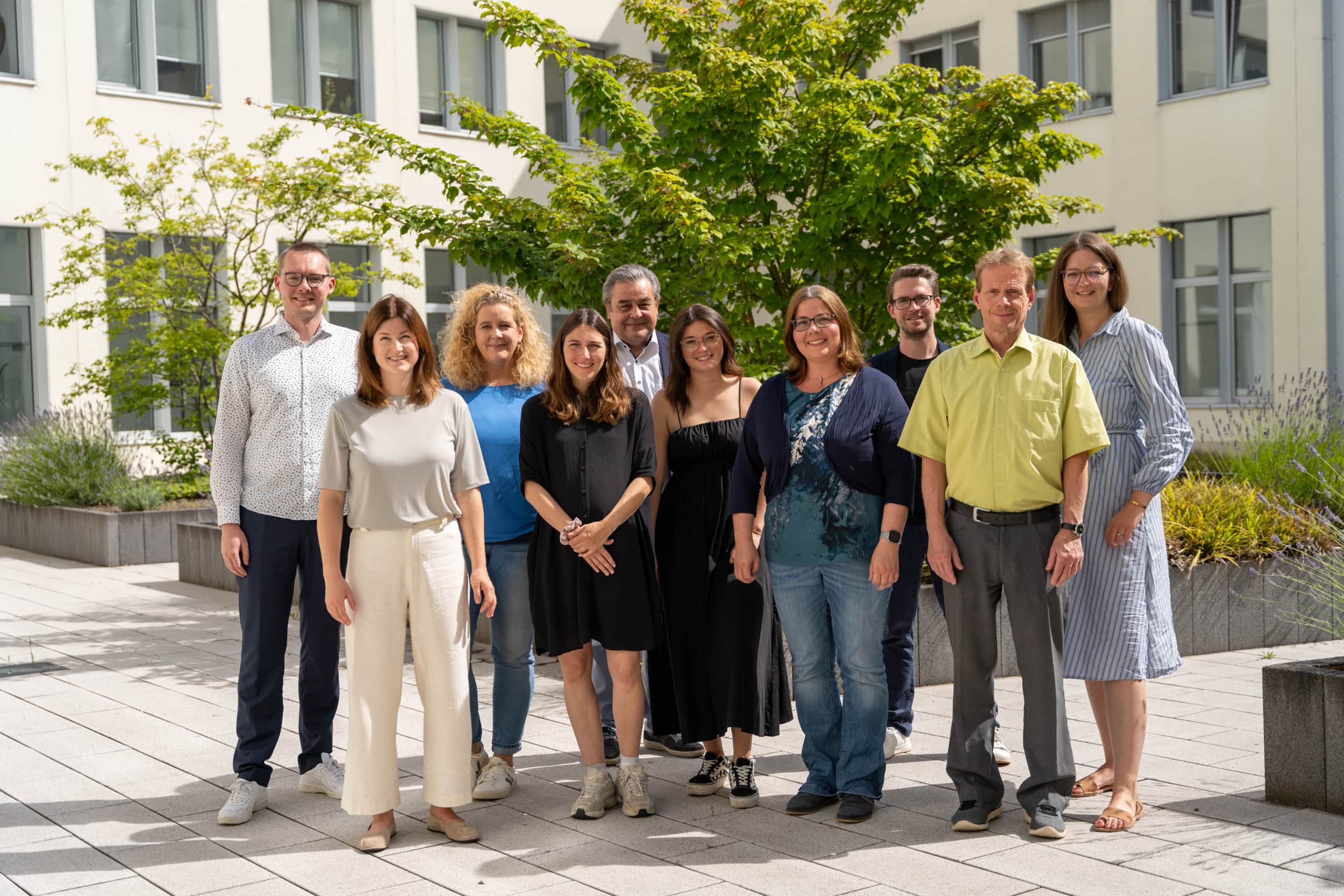 Das Team des innoclub in einem Hinterhof vor einem grünem Baum